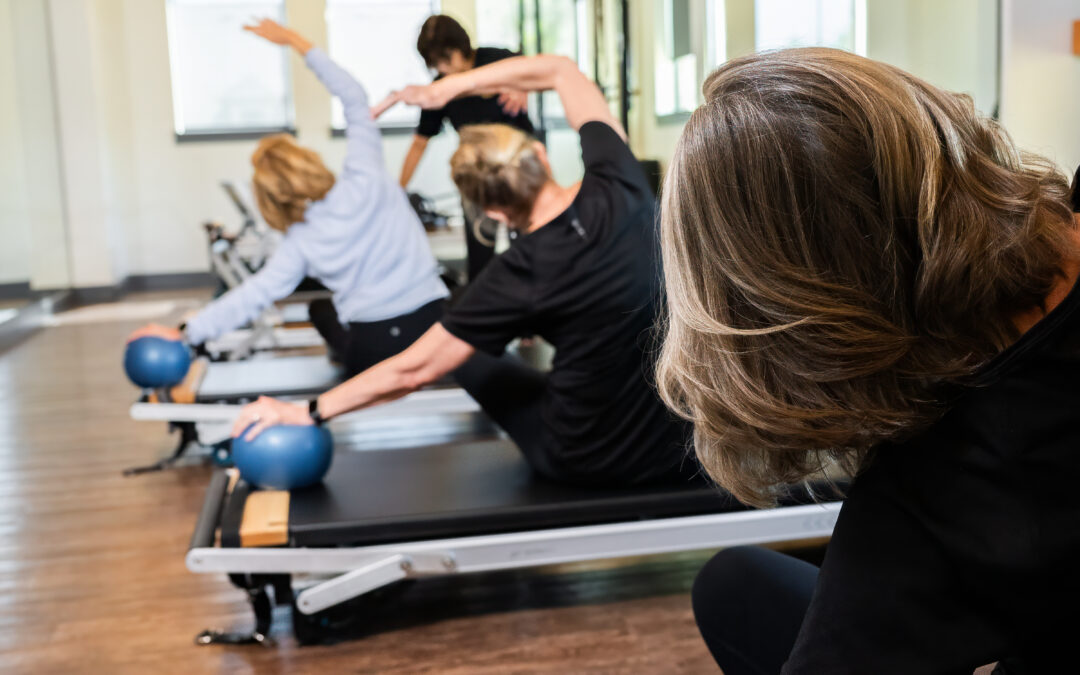 Group of individuals participating in a physical therapy session, using reformer machines and exercise balls to improve mobility and manage pain.