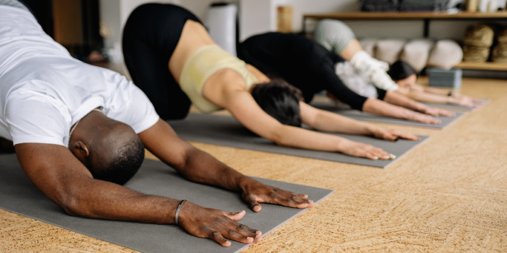 Group of individuals practicing physical therapy exercises in a studio, focusing on stretching and recovery techniques to enhance mobility and accelerate healing.